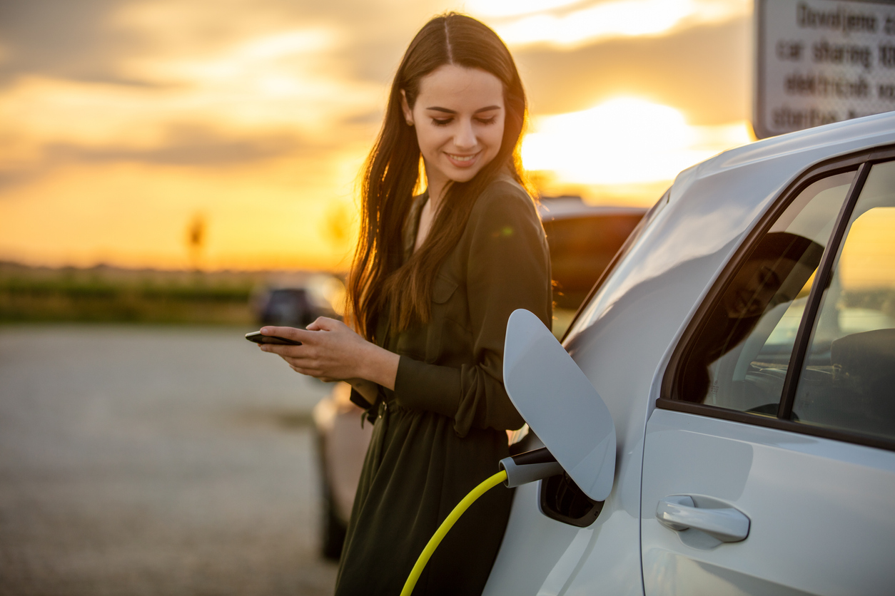 A woman charging her electric vehicle at an EV charging station.