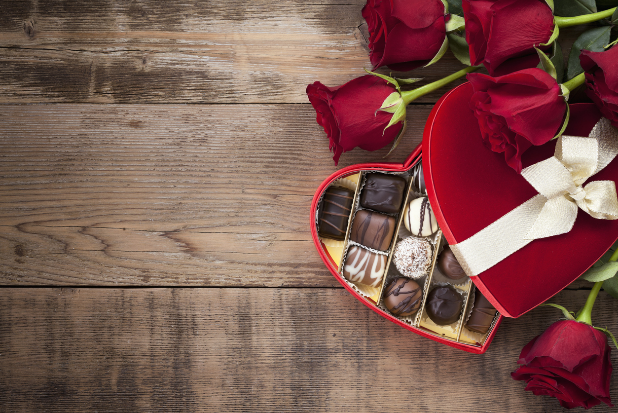 Valentine's day box of chocolates and red roses on a wood background