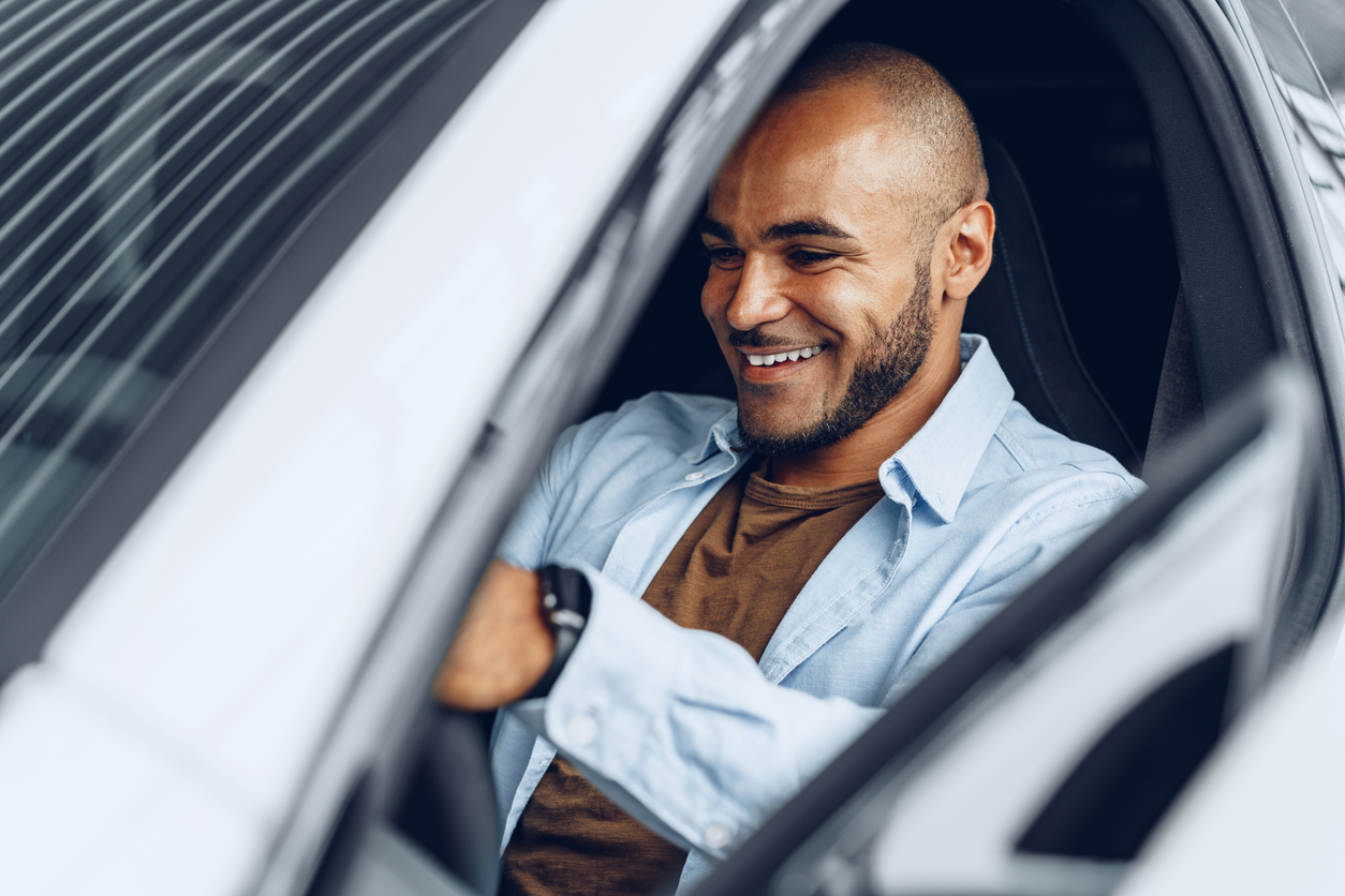 Portrait of a handsome happy African American man sitting in his newly bought car